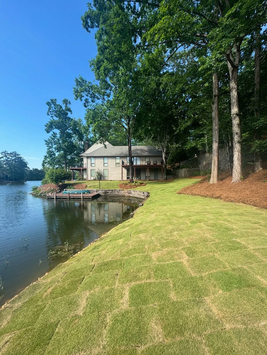 Fresh sod laid across a lakefront lawn running down to a dock.